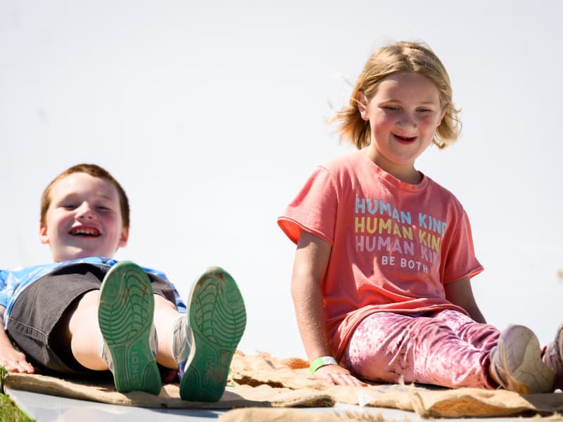 A boy and girl have big smiles as they prepare to go down the slide at Family Fun Day 2026.