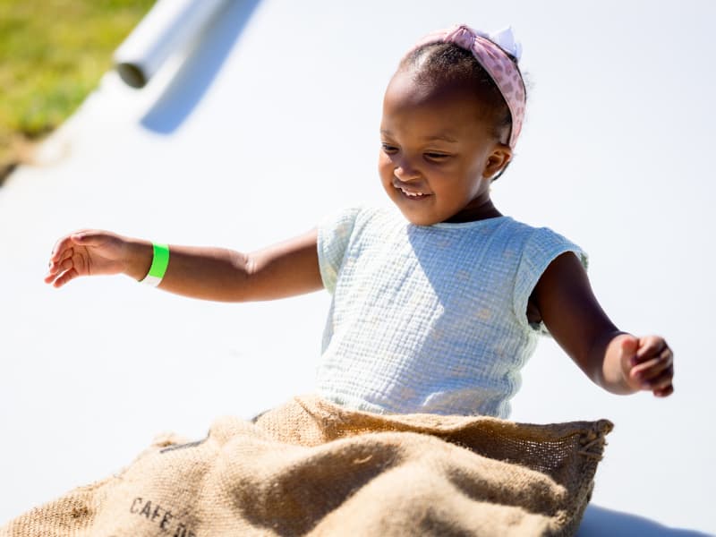 A girl smiles and lifts her arms as she goes down the slide at Family Fun Day 2026.