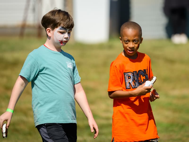 Two boys walk together eating ice cream sandwiches at Family Fun Day 2026.