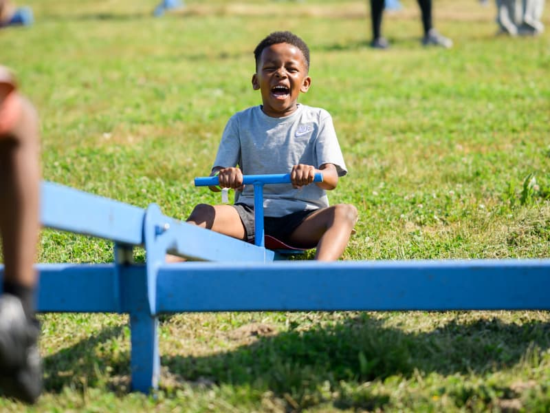 A boy has a big smile as he plays on a see-saw at Family Fun Day 2026.