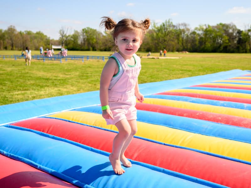 A girl with her hair in pigtails jumps on a bouncy toy at Family Fun Day 2026.