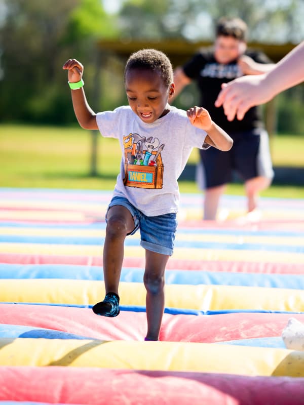 A boy smiles as he jumps on a bouncy toy at Family Fun Day 2026.