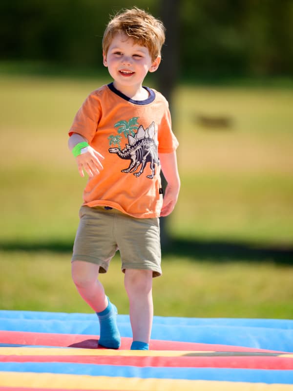 A boy wearing a dinosaur t-shirt jumps on a bouncy toy at Family Fun Day 2026.
