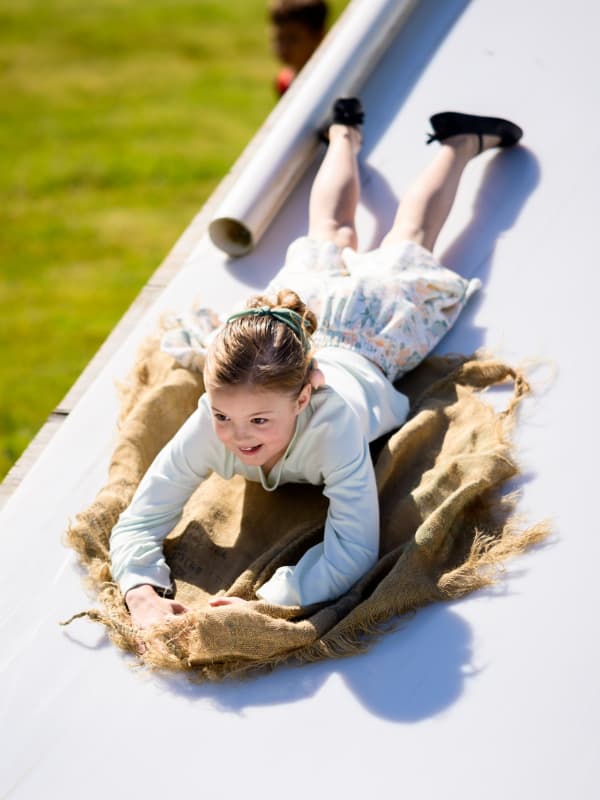 A girl smiles as she slide face-first down the slide at Family Fun Day 2026.