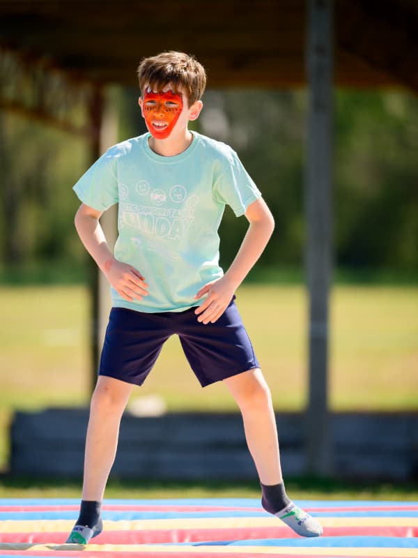 A boy with red face paint jumps on a bouncy toy at Family Fun Day 2026.