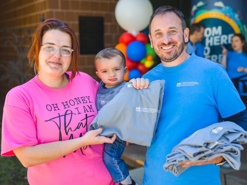 Dr. Ian Hoppe gives an event tshirt to a family at Family Fun Day