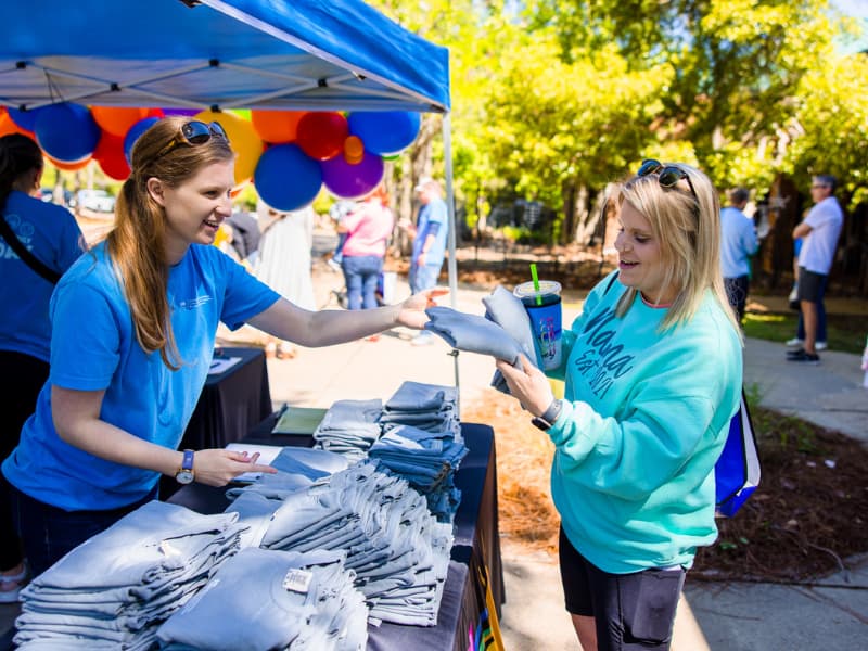 A woman registers at Family Fun Day and picks up her t-shirt