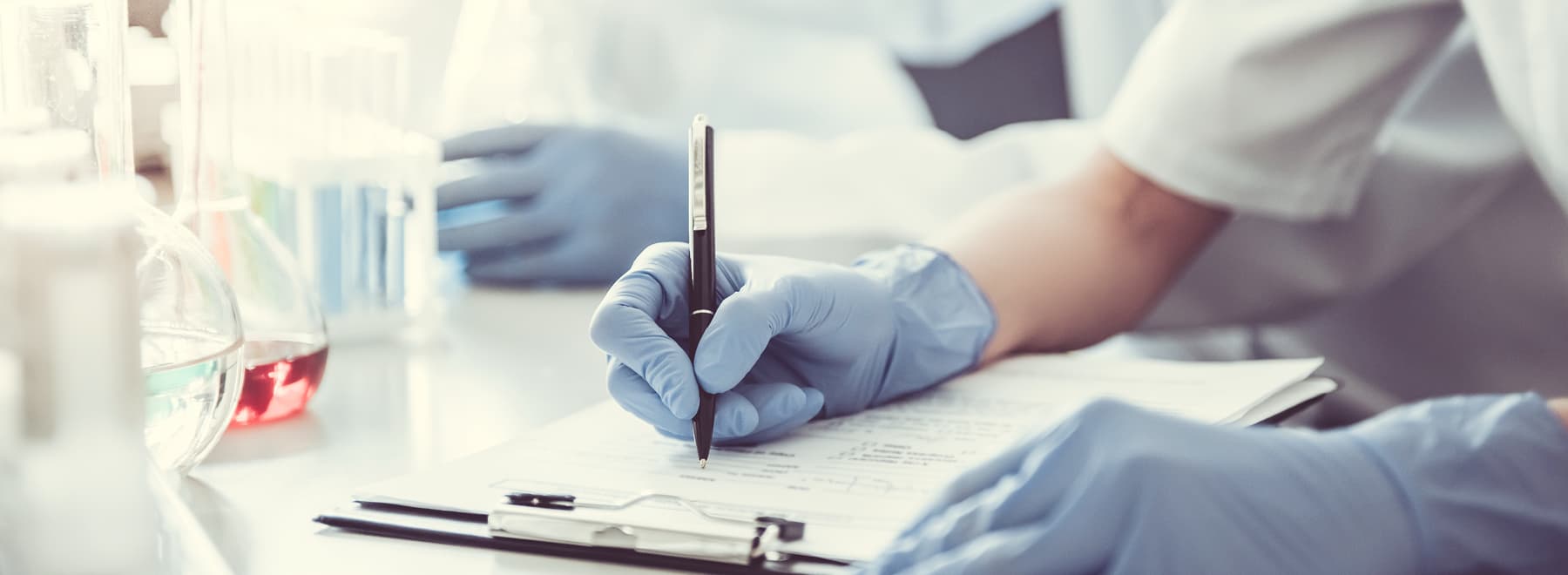 Close-up of a health care provider's arm making notes on a clipboard.