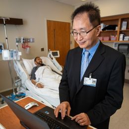 Dr. Shou-Ching Tang, who heads the UMMC Cancer Institute's Phase 1 clinical trials program, handles some of the documentation while his patient receives the infusion of a new drug he hopes will halt his cancer.