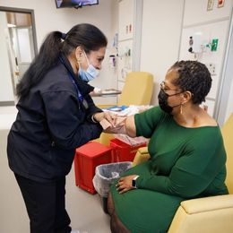 Shukla Faruque, left, a researcher in UMMC's Biobank, takes a blood sample from a participant in a COVID-19 research study, in UMMC's Clinical Research and Trials Unit.