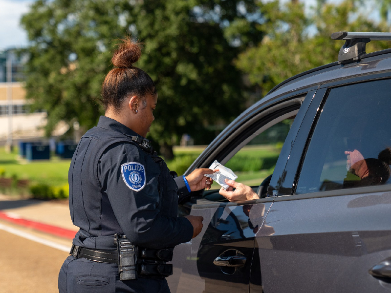 Photo of UMMC Police officer checking the license of a individual who was pulled over on campus. 