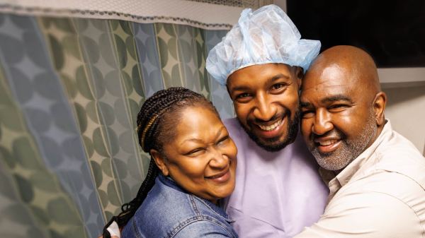 Smiling family hugs patient.