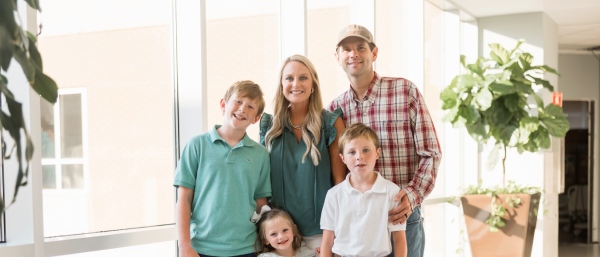 Patient and their family stand grouped together in front of a window.