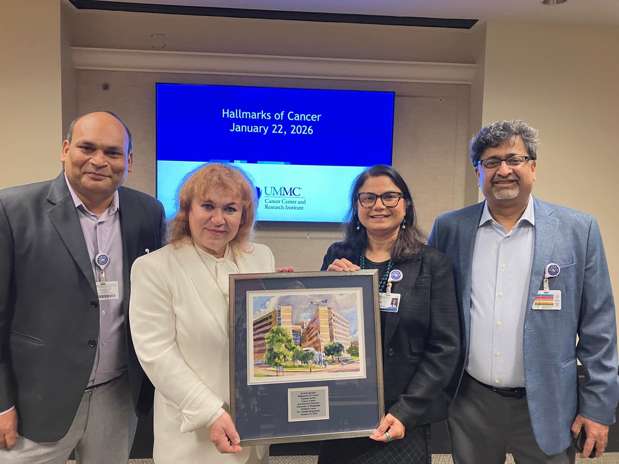 Dr. Natasha Kyprianou, second from left, is presented a watercolor print of the Medical Center. Welcoming her are, from left, Dr. Jawed Siddiqui, assistant professor of cell and molecular biology; Dr. Seema Singh, CCRI associate director of education and training; and Dr. Ajay Singh, CCRI associate director of basic and translational research.