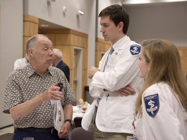 Dr. Gary Nye, left, Class of '65, makes a point with fourth-year medical student Lance Majors, center, and Hannah Greene, an M3.