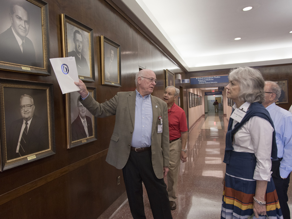 Pointing to portraits of past UMMC leaders, Dr. James Keeton, left, enlightens a group of alumni and spouses during a tour of the Medical Center. Among those looking on are Dr. Charles B. Itzig Jr., center, and Mary Abraham, right, wife of Dr. Ralph Ellis Abraham.