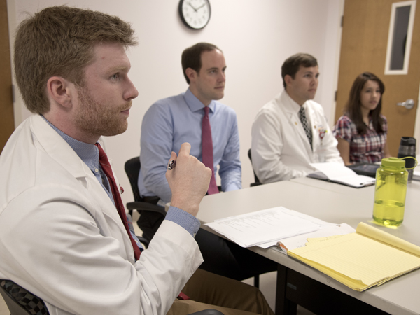 Students and faculty review symptoms of bipolar disorder during a round-table discussion in the group room of the Department of Psychiatry and Human Behavior. They are, from left, Daniel Kelly, a third-year medical student, Dr. Matthew Tull, associate professor of psychiatry and director of Anxiety Disorder Research and the Anxiety Disorders Treatment Clinic; Jeremy Archer, another third-year medical student, and Dr. Sadia Haque, a fourth-year psychiatry resident.