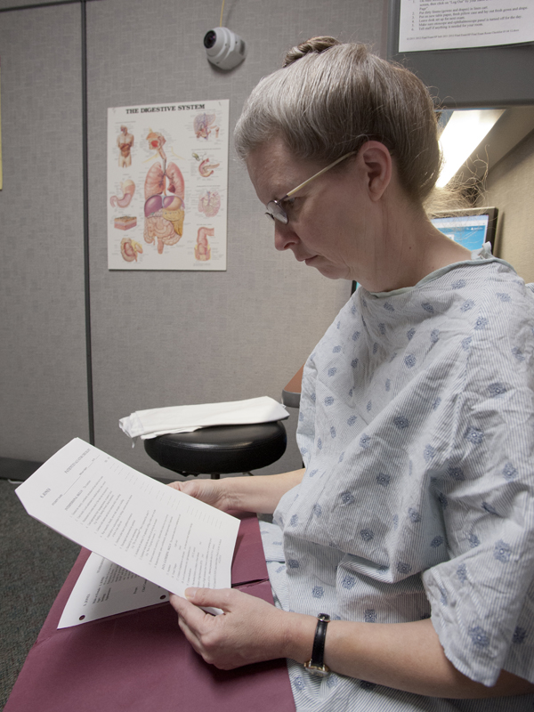 Bynum reads over an evaluation form used to gauge a student's aptitude for communicating with a patient and appraising a patient's condition.