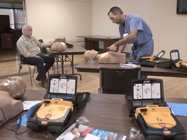 Jason Smith, right, emergency services manager, instructs a group of physical facilities employees, including Troy Bunn, how to use an AED.