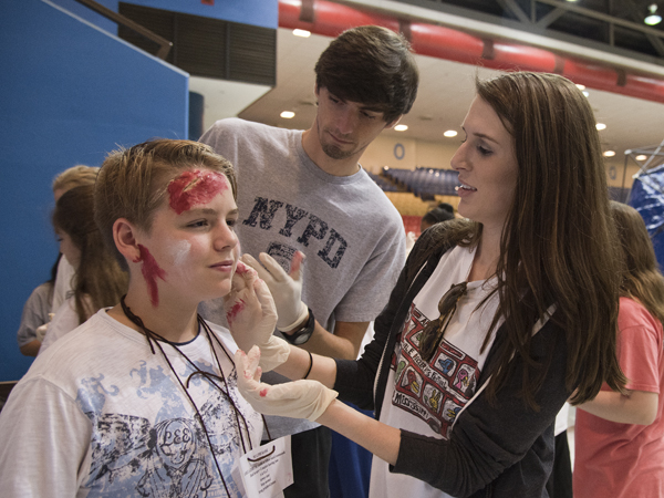 UMMC School of Nursing students Allen Lampton (center) and Maggie McDonald apply fake wounds and blood to the skin of Northwest Rankin Middle School eighth-grader Chris Russell