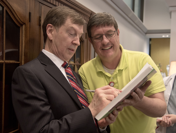 Dr. Robert Lewis, left, signs a copy of the Historical Atlas of Immunology for Dr. Stephen Stray, right,  associate professor of microbiology. The book was co-authored by Lewis and Dr. Julius Cruse, both of whom were honored by a retirement reception Thursday in the Rowland Medical Library.