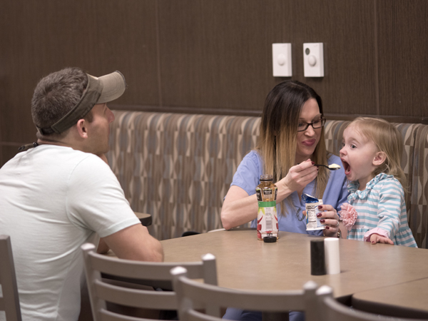 Allen (center) and 3-year-old daughter Maddie share a cup of yogurt in the UMMC cafeteria before Allen begins a night shift. Her husband and Maddie’s father, Bear Allen, often brings Maddie to the hospital to visit when she works double shifts.