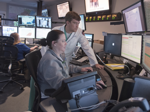 Dr. Damon Darsey, assistant professor of emergency medicine and medical director for the Mississippi Center for Emergency Services, confers with MED-COM communications specialist Amy Shook as she monitors patient transfers.