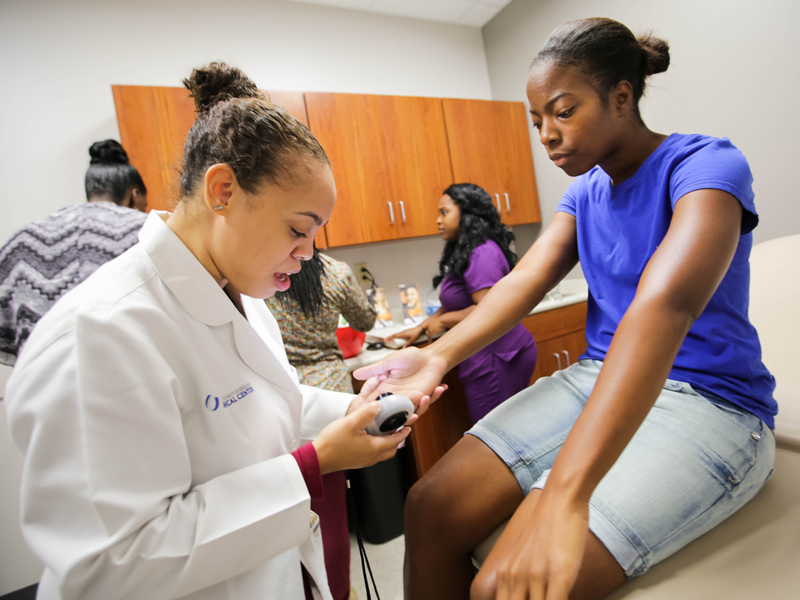 Dr. Jasmine Hollinger of the Medical Center’s Department of Dermatology examines Belzoni resident Twyla Courts during a health fair that accompanied the ribbon cutting for the UMMC Community Care Clinic.
