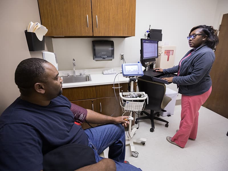 Certified Medical Assistant Lakendra Taylor checks patient Michael Hayes' blood pressure.