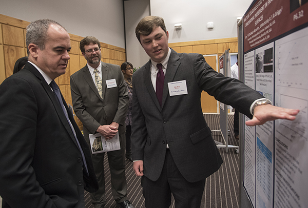 Nör and Griggs listen as Bo Key presents his research. Key, a senior at Mississippi State University, will join UMMC as a first-year dental student this fall.
