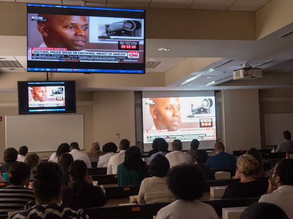 Lecture attendees watch a CNN recording of Williams' news conference.