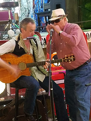 Bowman, right, plays his harmonica alongside another musician while on vacation.