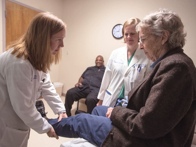 Dr. Carter P. Milner, left, examines swelling in Gloria Brown's leg as nurse practitioner Dana Delanski looks on.