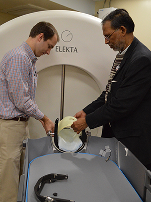 Physicist Neil Duggar, left, assistant professor of radiation oncology, and Dr. Srinivasan Vijayakumar, chair of the Department of Radiation Oncology, check fittings on a mask on the department's Elekta Gamma Knife.