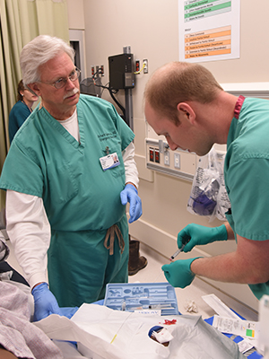 Summers and Dr. Ryan Green, an Emergency Medicine resident, tend to a patient in the ER.