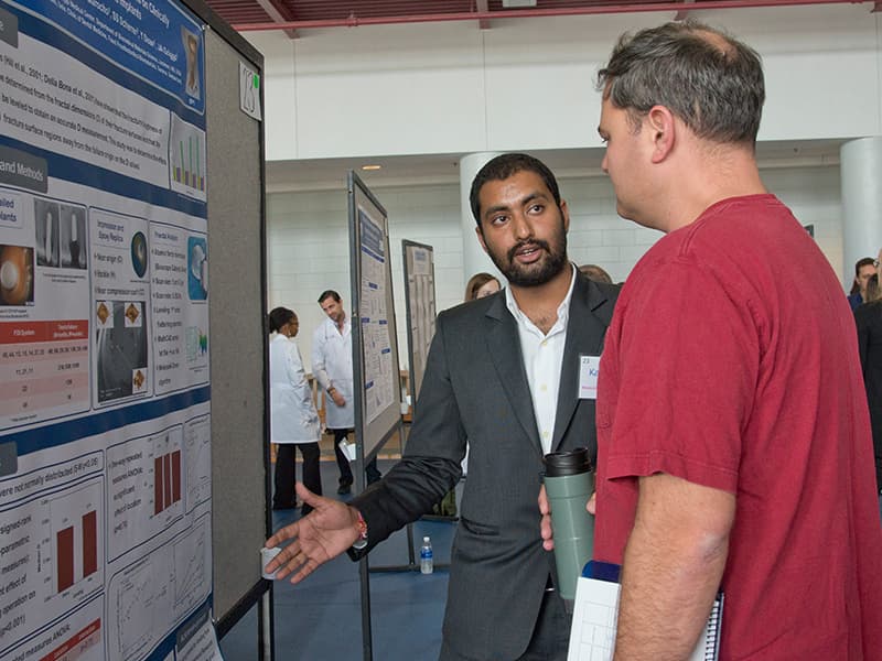 Kartikeya Johda, a second-year Ph.D. student in biomedical materials science, shares his research on dental implants with Dr. Eric George, assistant professor of physiology and biophysics and poster judge.