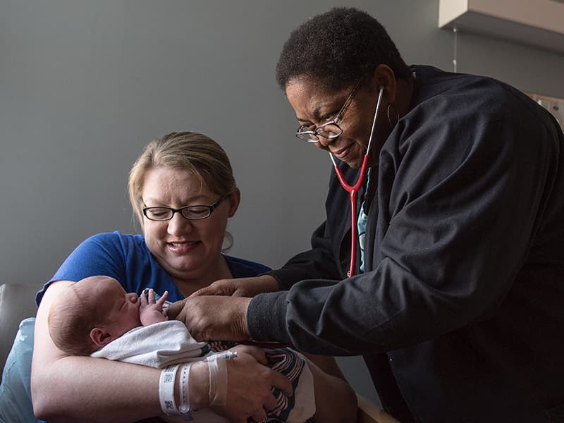 Nurse Virgle Smoot checks Renner's vital signs as he is cradled by mom Amanda Vowell.