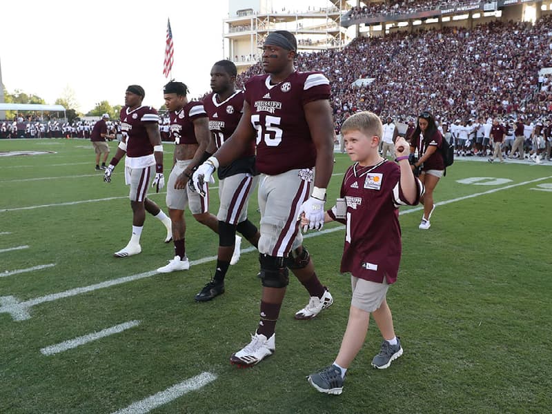 Kid Captain Thomas Blanks of Madison walks across Scott Field with Bulldogs at the Sept. 16 game against LSU.