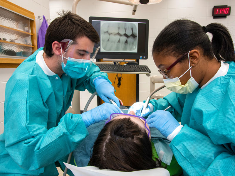 First-year dental student John Mathis assists Dr. Akilah Stringer, resident, with patient Chasity Bishop of Florence during Dental Mission Week at the School of Dentistry in February.