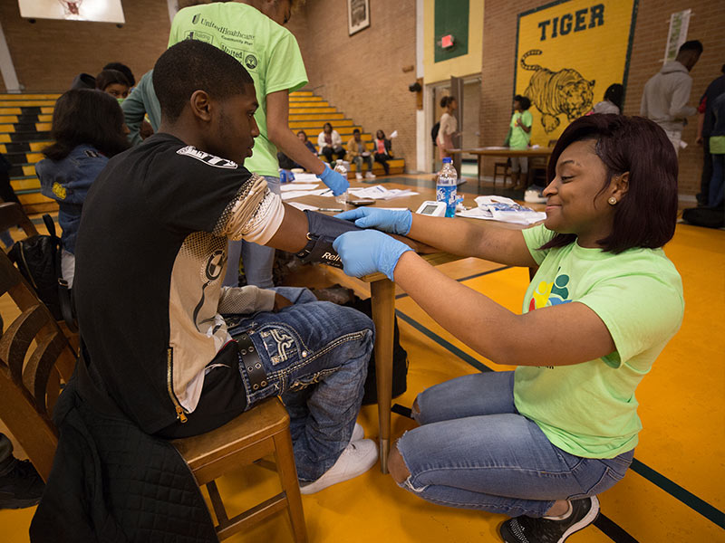 Janiyah Harris adjusts a blood pressure cuff for Tyree Williams during a wellness fair at Jim Hill High School.
