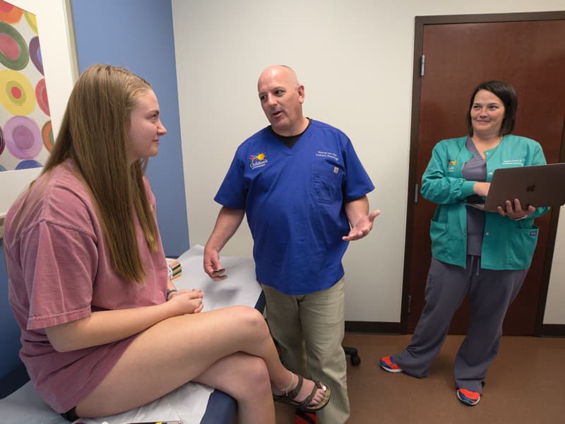 Pediatric neurologist Dr. Mark Lee talks with patient Kate Brown of Lucedale at the Children's of Mississippi specialty clinic in Biloxi. Looking on is nurse Jamie Cook.