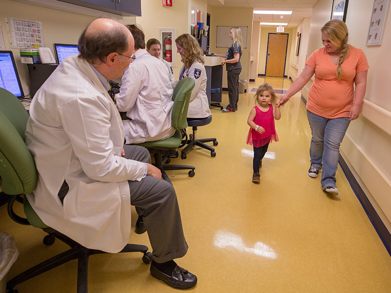 Dr. Edwin Harmon, professor and chief of pediatric urology, greets patient Caleigh Kelly of Mount Olive and her mother, Savannah Hollingsworth, at the Eli Manning Children's Clinics.