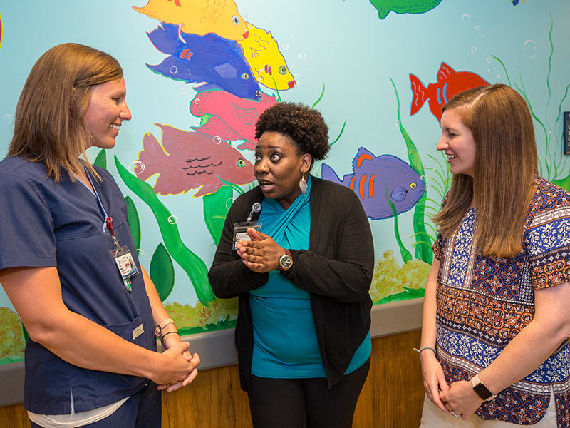 Dobbins talks to friends, Katie Williams, left, a nurse and pediatric care coordinator, and Sarah Elkin, a nurse practitioner in the pediatric hematology and oncology division.