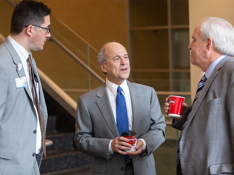 Dr. Peter Arnold, left, and Dr. Michael Henderson, right, chat with Chassin during a meeting with UMMC administrators.