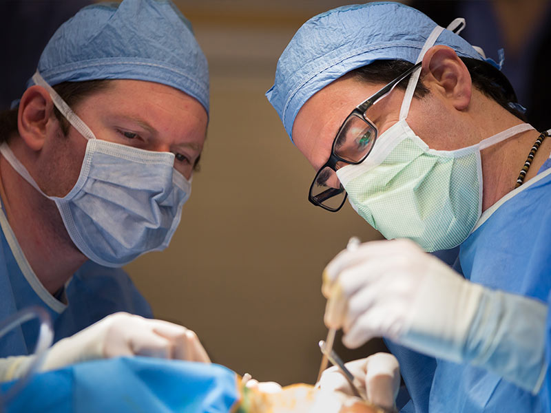 Dr. David Kowalczyck, left, fifth-year otolaryngology resident, works alongside Dr. Jeff Carron during a cochlear implant surgery.