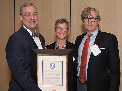 Dr. Tim Folse, left, outgoing president of the Medical Alumni Chapter, presents a Hall of Fame award to the children of the late Dr. Herbert Langford: from left, Ellen Langford and Robert Langford.