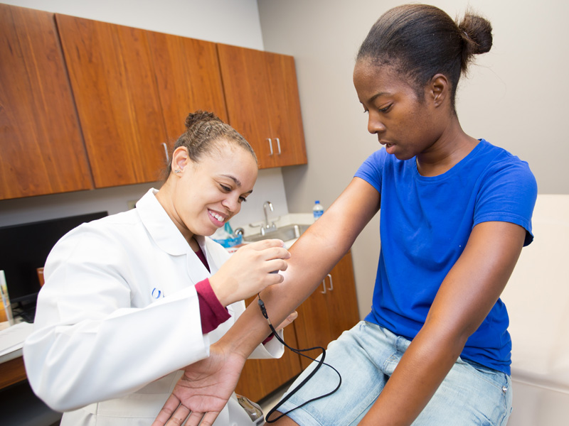 Dr. Jasmine Hollinger, assistant professor of dermatology, examines Belzoni resident Twyla Courts during a health fair that accompanied the ribbon cutting for the UMMC Community Care Clinic.