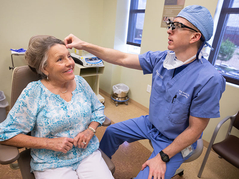 Dr. William Black, right, examines Linda Puckett's forehead. Black used Mohs surgery to remove a melanoma from the area.