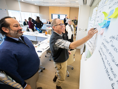 Dr. Pierre de Delva, left, and Dr. James Wynn write ideas on a white board during leadership training.