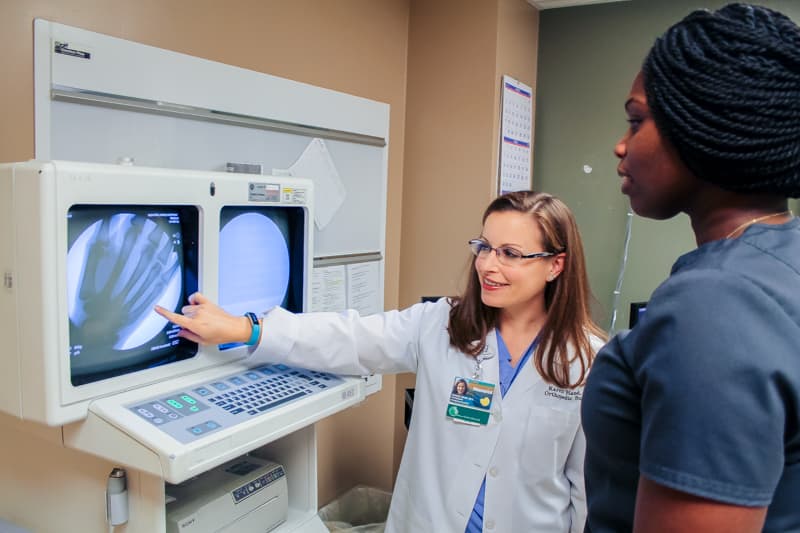 Dr. Karen Hand explains a scan of a hand to Chela Howell, a multi-skilled technician and fellow employee at Gulfport’s Memorial Hospital.